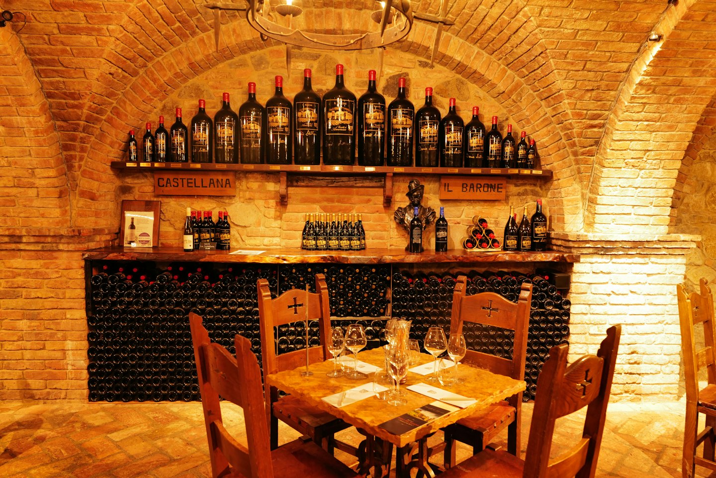 Wine glasses are set on a wooden table in a cellar.