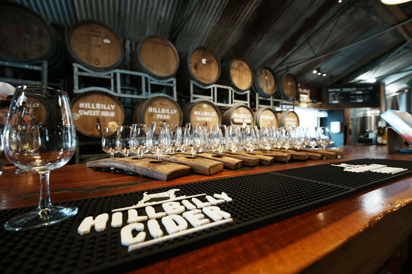 Empty wine glasses sit on wooden tasting flights at a bar.